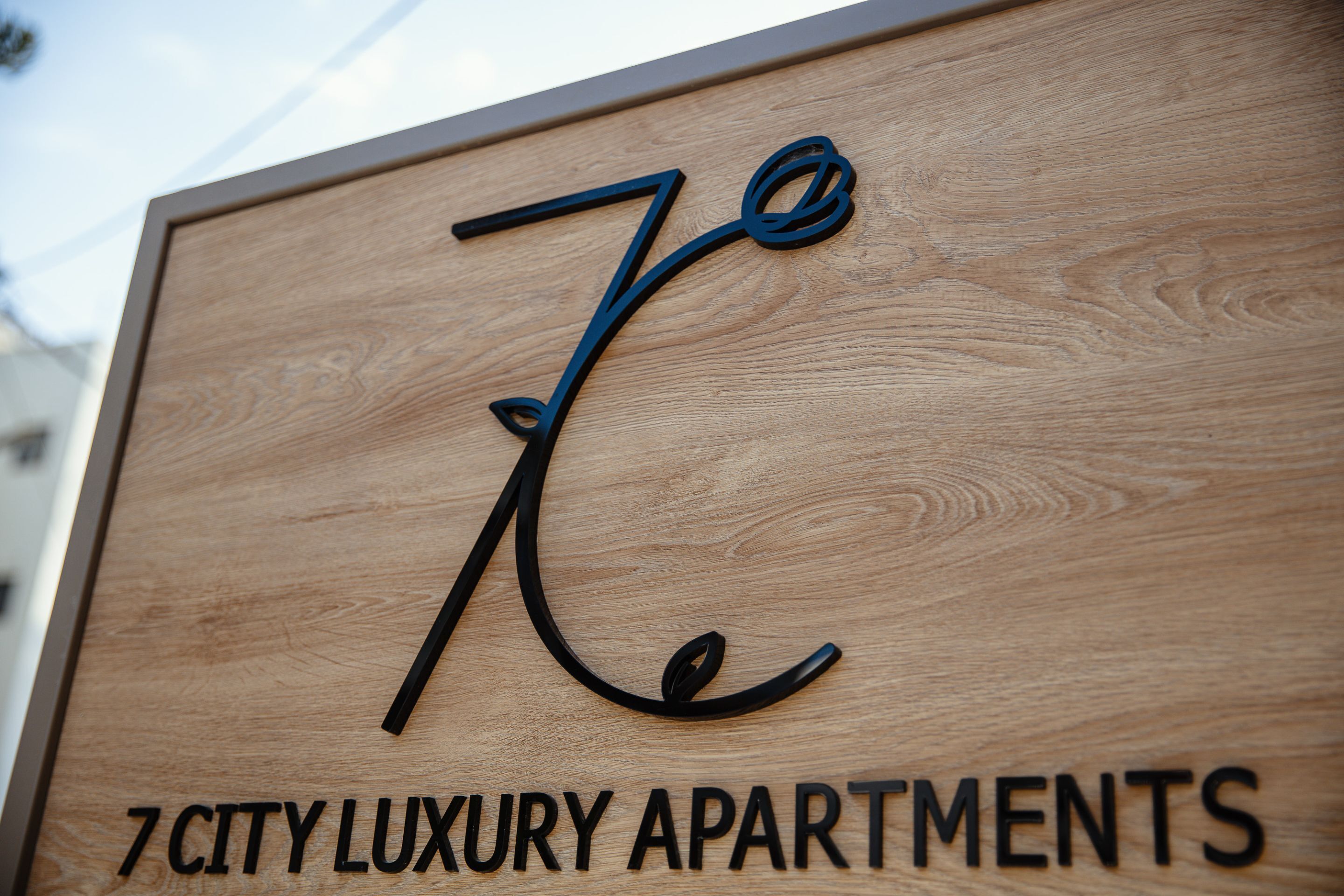 A wooden sign with the number "7" and the text "CITY LUXURY APARTMENTS".