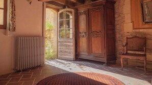 Une pièce rustique avec un plafond en bois, une grande armoire en bois, une chaise en osier et un radiateur.