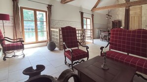 Un ampio soggiorno con camino, poltrone rosse rivestite in tessuto, un tavolino in legno e un'area pranzo con tavolo e sedie.