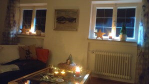 Un saló acollidor amb una llar de foc, una finestra decorada amb estels i un petit arbre de Nadal.