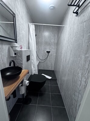 A modern bathroom with a black sink, toilet, and shower. - Capitol Zentrum - 24h - (Friedrichshafen)