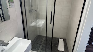 A modern bathroom with a glass-enclosed shower, a white sink, and a mirror. - Capitol Zentrum - 24h - (Friedrichshafen)