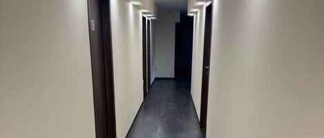 A long, narrow hallway with dark grey flooring and light-colored walls.