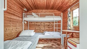 Eine Hütte mit Etagenbett, einem Einzelbett, einem Schreibtisch und einem Fenster mit Vorhängen.