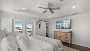 Un dormitorio con cama, ventilador de techo, cómoda y un cuadro en la pared.