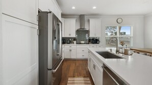 Una cocina moderna con armarios blancos, electrodomésticos de acero inoxidable y una isla grande con un lavamanos.