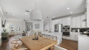 Una cocina moderna con armarios blancos, una mesa de comedor de madera y una lámpara colgante.