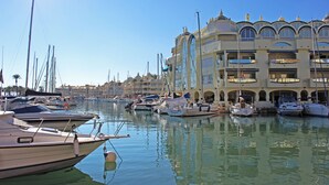 A marina with multiple boats docked, a large building with balconies, and clear skies. - Stunning sea views @ Stupa hills (Benalmádena)