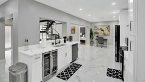 A modern kitchen with white cabinetry, a built-in dishwasher, and a stainless steel range hood. - LUX 6BR 4Bath Htd Pool & SPA Mini Golf G-Room (Deerfield Beach)