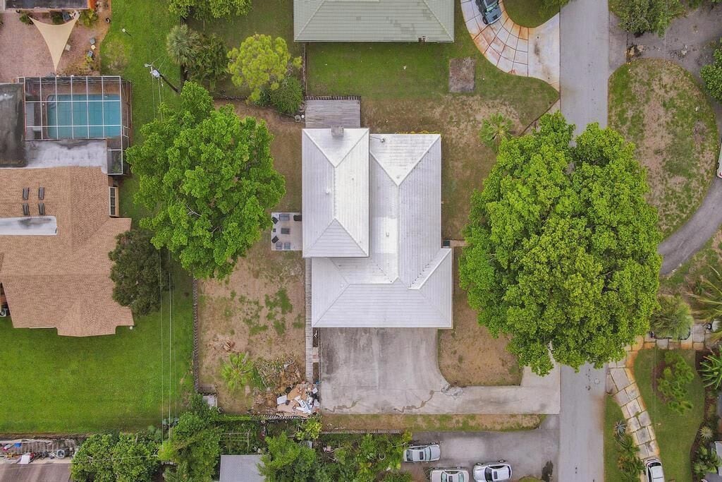 An aerial view of a property with a central building, a swimming pool, and surrounding greenery.
