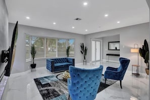 Una sala de estar moderna con un sofá azul, una mesa de centro redonda y un sillón azul.