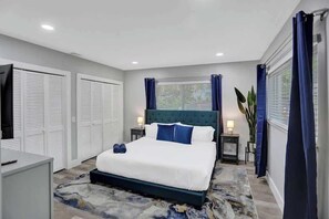 A bedroom with a bed, bedside tables, a TV, and a window with curtains.