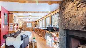 Un salon chaleureux avec une cheminée, un plancher en bois et un mur en pierre.