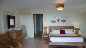 A hotel room with a large bed, wooden furniture, a painting on the wall, and a ceiling light. - Villa Alizés 8 pers. 4 air-conditioned bedrooms (Le Gosier)