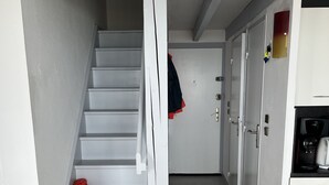 A staircase leading to a door, a white chair, and a kitchen area with appliances. - HOUSE WITH MAGNIFICENT SEA VIEW (Le Barcarès)