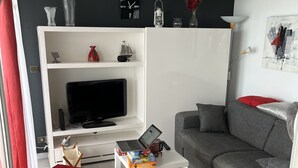 A modern living room with a grey sofa, red ottomans, a white coffee table, and a TV on a white stand. - HOUSE WITH MAGNIFICENT SEA VIEW (Le Barcarès)
