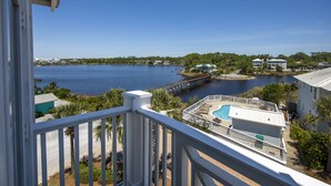 A view from a balcony overlooking a lake with a swimming pool, a dock, and surrounding buildings. - New to Dune Allen Realty!!! (Santa Rosa Beach)