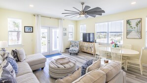 A spacious living room with a large sofa, ottoman, and a dining area with a table and chairs. - New to Dune Allen Realty!!! (Santa Rosa Beach)
