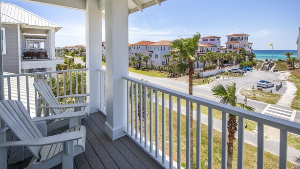 A balcony with white railings overlooking a beach and a road with parked cars. - New to Dune Allen Realty!!! (Santa Rosa Beach)
