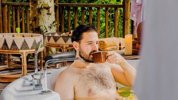 Guests can unwind in a bathtub surrounded by amenities, including a modern faucet and comfortable seating.