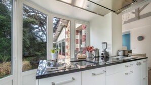 Une cuisine moderne dotée d’une grande fenêtre, d’appareils électroménagers en acier inoxydable et de meubles blancs.