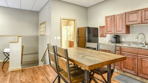 Une cuisine dotée de meubles de rangement en bois, d’un réfrigérateur et d’un coin repas avec une table et des chaises.