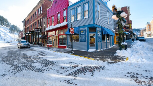 Une vue d’une rue avec un bâtiment sur lequel on peut voir une enseigne indiquant « Visites guidées sur le thème des fantômes », une autre indiquant « Entrée interdite » et une troisième indiquant « Bienvenue ».