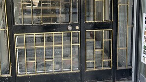 Un portail en métal noir avec un panneau en verre et un clavier pour ouvrir la serrure.