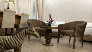 Une pièce avec deux fauteuils à rayures, une table basse en verre et une figurine de zèbre posée sur une table.