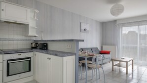 Una cocina moderna con armarios blancos, horno empotrado y comedor con mesa y sillas.
