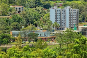A multi-story building with a modern architectural design, surrounded by lush greenery and other residential structures. - Century Park Hotel and Residences (Kigali)