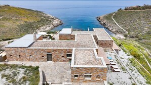 A coastal building with a stone facade, multiple levels, and a view of the sea. - Villa LENA:Beachfront Villa 70 m to sandy isolated Beaches C/spa outdoor jacuzzi (Kea)