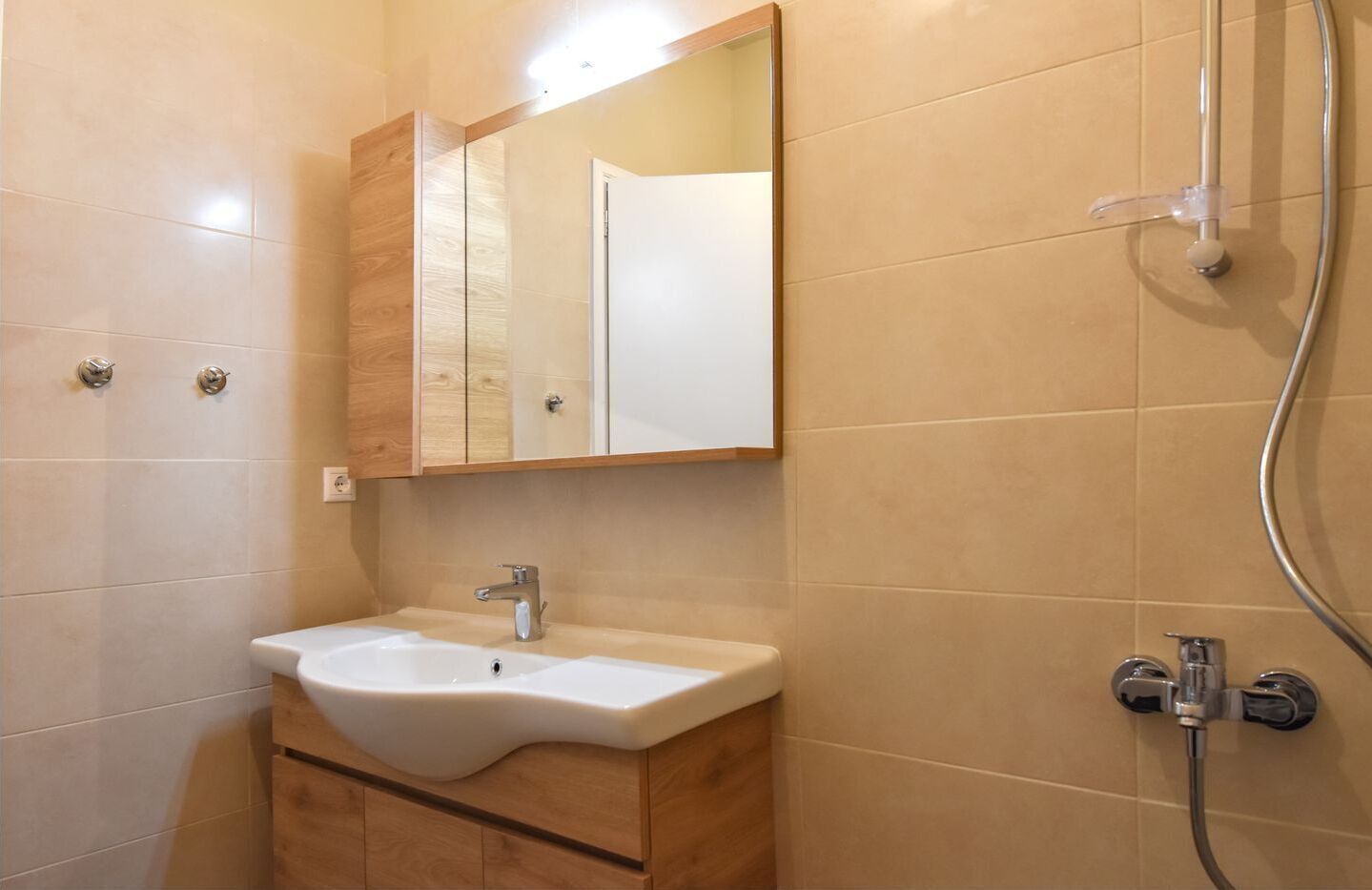 A bathroom with a white sink, a mirror, and a shower.