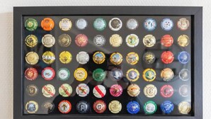 Una colección de tapas de botellas de cerveza dispuestas en un marco negro.