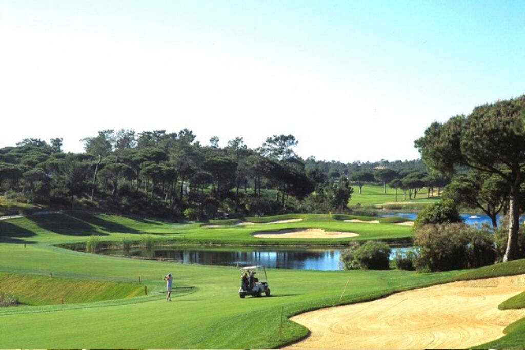 A golf course with a pond, sand bunkers, and a golf cart.