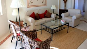 A living room with a sofa, two armchairs, a glass coffee table, and two floor lamps. - Presley Pink Apartment, Quinta do Lago, Algarve (Algarve)