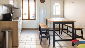 Eine Küche mit Holztisch, Hocker und einem Mülleimer.