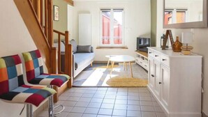 Ein kompakter Wohnraum mit einer Couch, einem kleinen Tisch, einem Fernseher und einem Schrank.