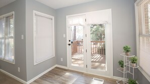 Un pasillo con pared gris, molduras blancas y suelo de madera. Hay una puerta blanca con paneles de vidrio que da a una terraza exterior.