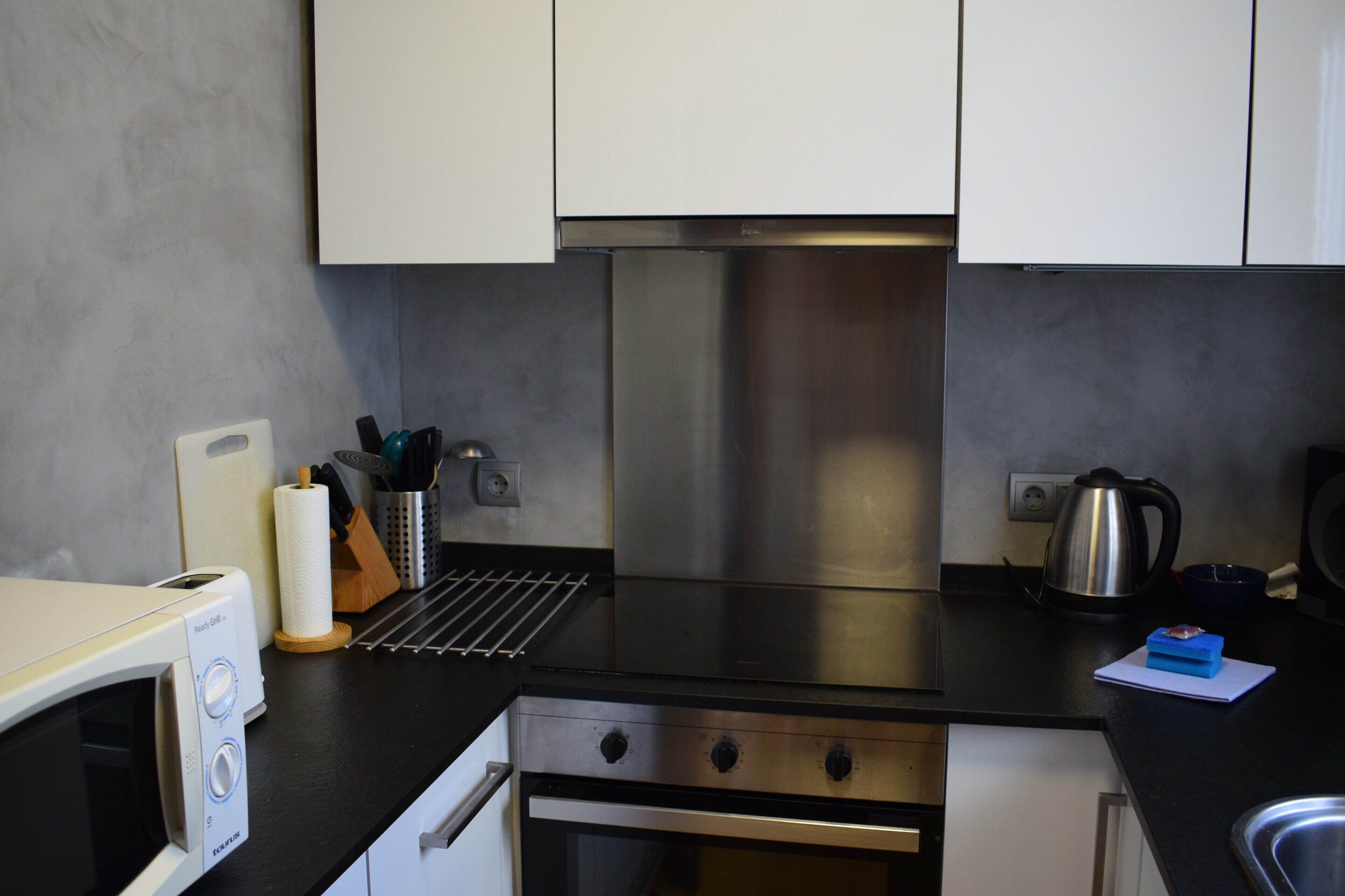 A modern kitchen with stainless steel appliances, a microwave, and a kettle.