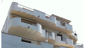 A multi-story building with balconies and a stone wall with plants. - CANYELLES PETITES - ROSAS 3mn plage Vue mer Tout confort GARAGE Terrasse 40m2 (Roses)