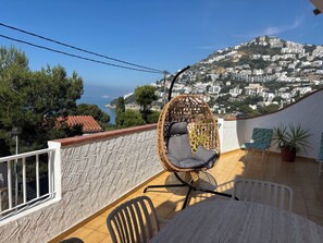 Un balcone con una sedia in vimini, un tavolo e piante in vaso.