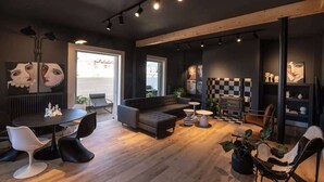 A modern living room with a sofa, dining table, and chairs. There are plants and artwork on the walls. - City's Best-Kept Secret, Chic & Luxe Getaway (Kalamata)