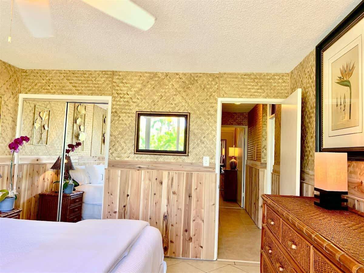 Una habitación de hotel con cama, cómoda de madera, espejo y un cuadro en la pared.