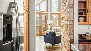 A kitchen with a stainless steel refrigerator, wooden cabinets, and a stone wall. - Western Sky Ranch | 8 Bed | Pool Table + Deck (Breckenridge)