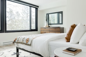 A bedroom with a bed, a dresser, a round table, and a window with a view of trees. - Keystone Lake w/ MTN View | Pool+Hot Tub+Gym+Sauna (Dillon)