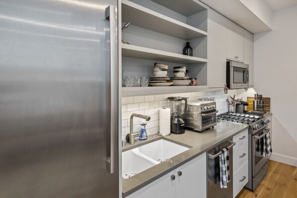 Een moderne keuken met roestvrijstalen apparatuur, een ingebouwde magnetron en een spoelbak.