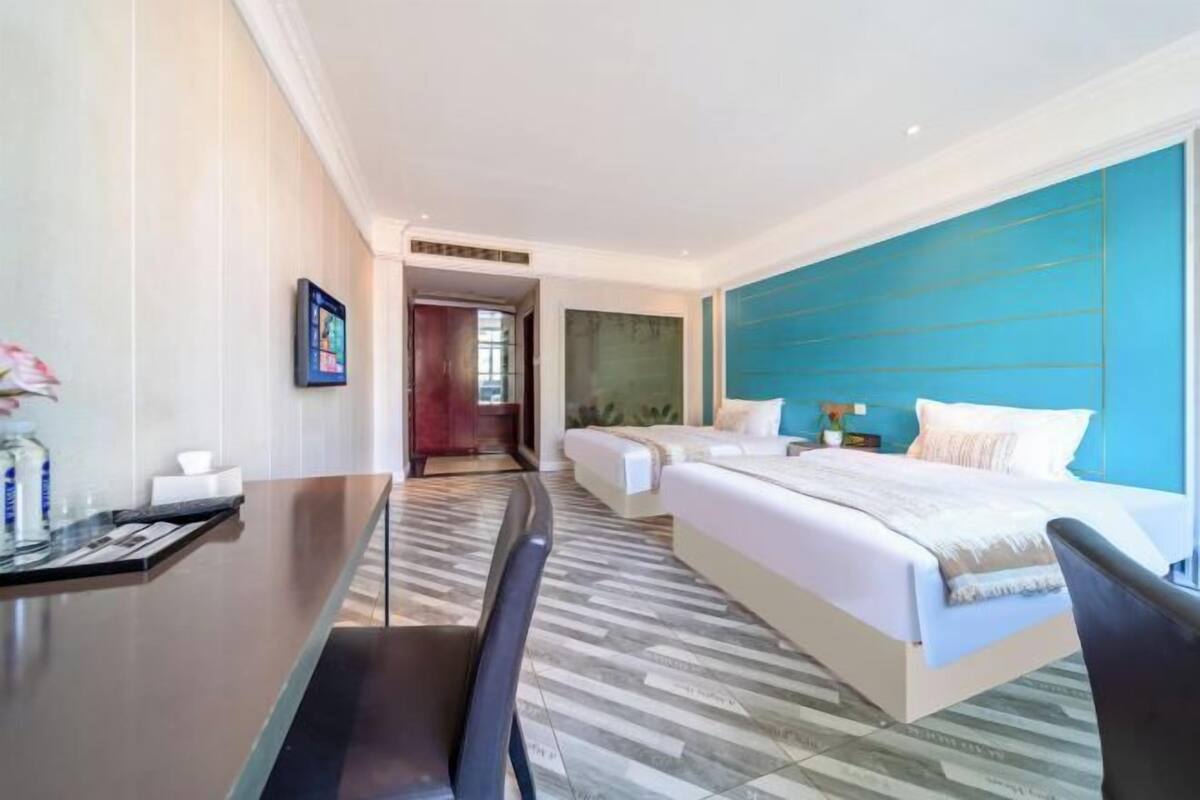 A hotel room with a bed, a desk, a chair, a TV, and a bathroom.