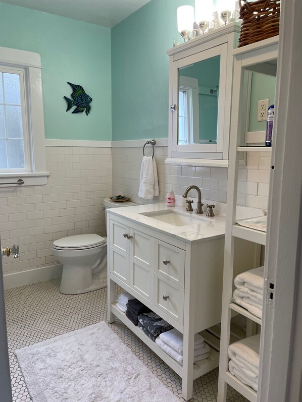 A bathroom with a white vanity, a toilet, and a sink with a mirror above it.