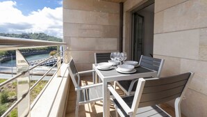 Een balkon met een tafel voor vier personen, uitkijkend op een rivier en groen.